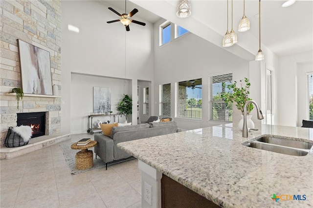 3437 De Soto Loop, Round Rock, TX 78665 - kitchen featuring a ceiling fan, a fireplace, light stone counters, light tile patterned flooring, and high vaulted ceiling