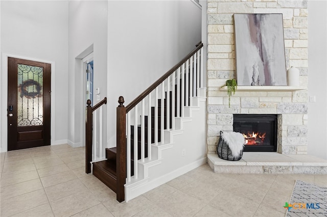 3437 De Soto Loop, Round Rock, TX 78665 - tiled foyer entrance featuring a stone fireplace, stairs, a high ceiling, and baseboards