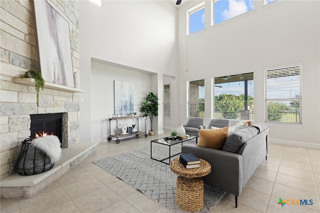 3437 De Soto Loop, Round Rock, TX 78665 - living area featuring light tile patterned floors, a stone fireplace, a high ceiling, and baseboards