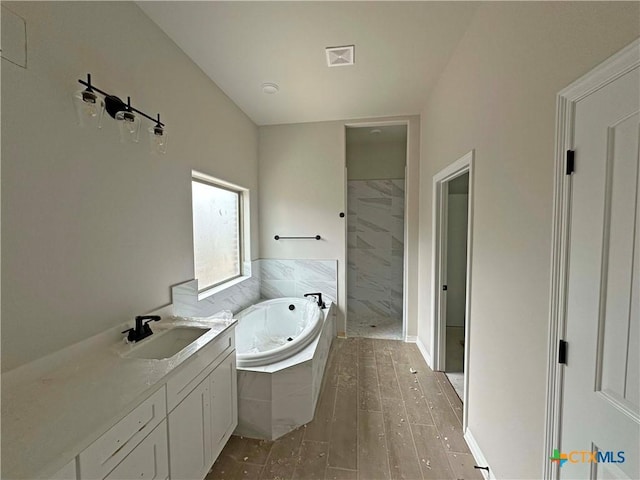 bathroom featuring a marble finish shower, visible vents, wood finished floors, a garden tub, and vanity