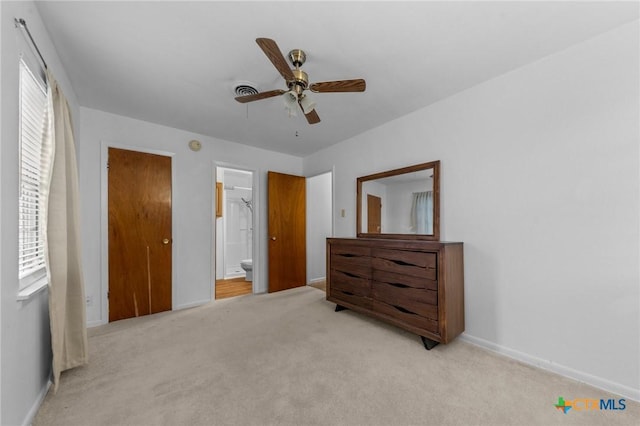 carpeted bedroom with ensuite bathroom and ceiling fan