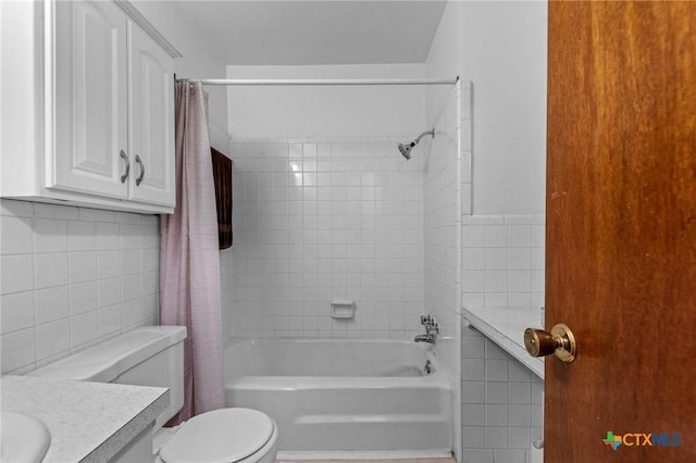 full bathroom featuring shower / bath combination with curtain, vanity, toilet, and tile walls