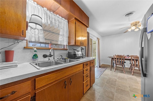 kitchen with tasteful backsplash, stainless steel fridge, ceiling fan, and sink