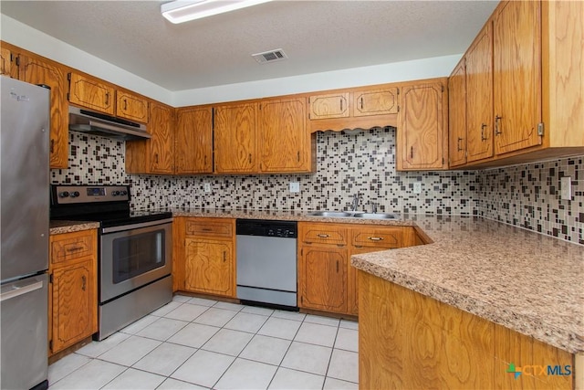 2009 Fleetwood Dr, Killeen, TX 76543 - kitchen with stainless steel appliances, under cabinet range hood, brown cabinets, and tasteful backsplash