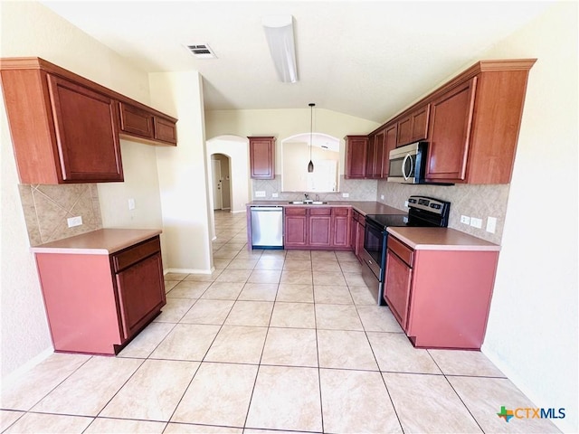 kitchen with pendant lighting, sink, appliances with stainless steel finishes, light tile patterned flooring, and vaulted ceiling