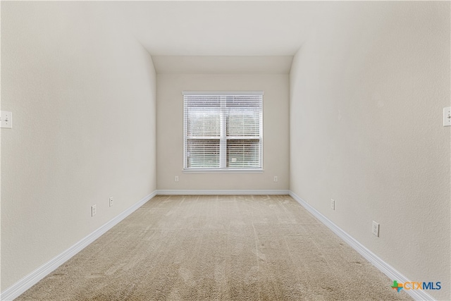 carpeted empty room with vaulted ceiling