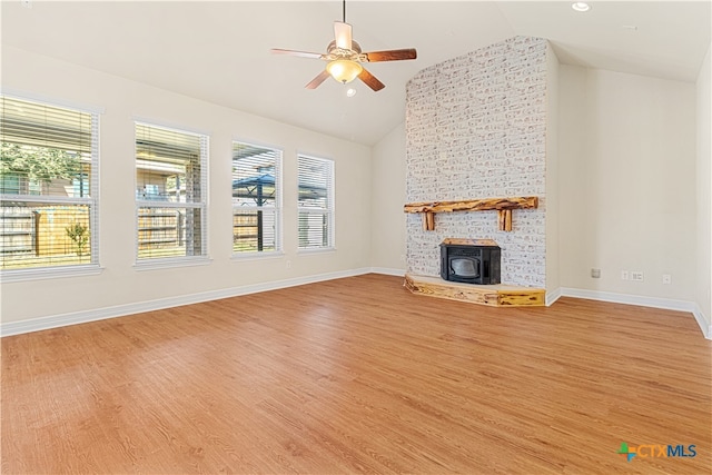 unfurnished living room with hardwood / wood-style flooring, lofted ceiling, ceiling fan, and a wood stove