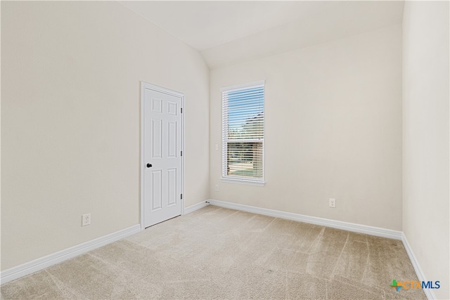 spare room featuring carpet floors and lofted ceiling