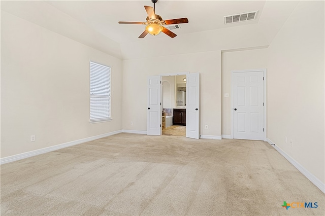 unfurnished bedroom featuring ensuite bath, light carpet, and ceiling fan