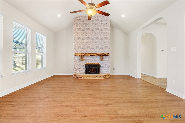 unfurnished living room with light hardwood / wood-style floors, a wood stove, and vaulted ceiling