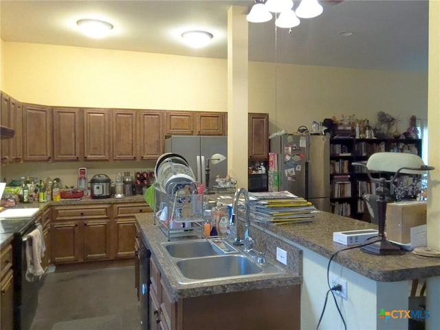 618 Pecos St, Lockhart, TX 78644 - kitchen featuring a sink, brown cabinetry, freestanding refrigerator, and an island with sink