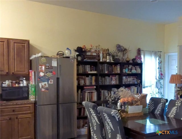 618 Pecos St, Lockhart, TX 78644 - interior space featuring brown cabinets, black microwave, and freestanding refrigerator