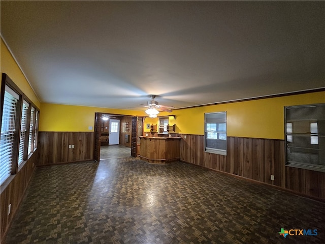 220 Davis Ave, Port Lavaca, TX 77979 - unfurnished living room featuring a wainscoted wall, wooden walls, ceiling fan, and baseboards