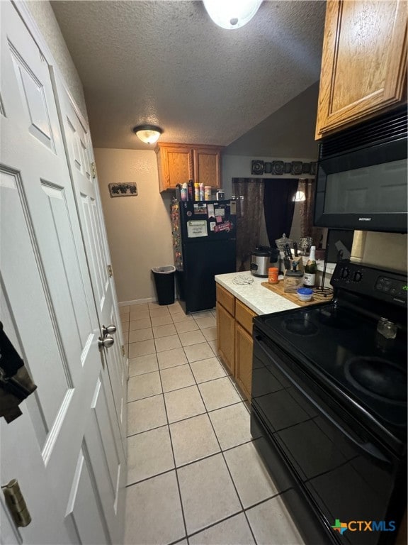 kitchen featuring a textured ceiling, light tile patterned floors, and black appliances