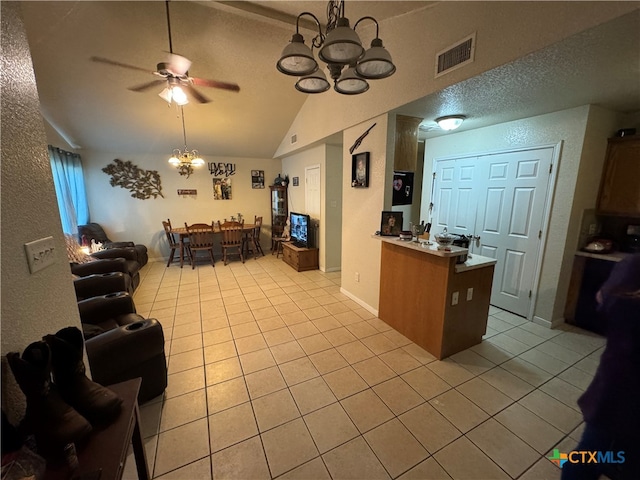 kitchen with a textured ceiling, ceiling fan with notable chandelier, light tile patterned flooring, and vaulted ceiling