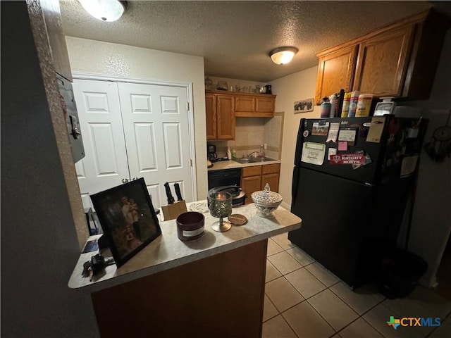 1617 S Harley Dr, Harker Heights, TX 76548 - kitchen featuring freestanding refrigerator, light tile patterned floors, a textured ceiling, brown cabinetry, and a peninsula