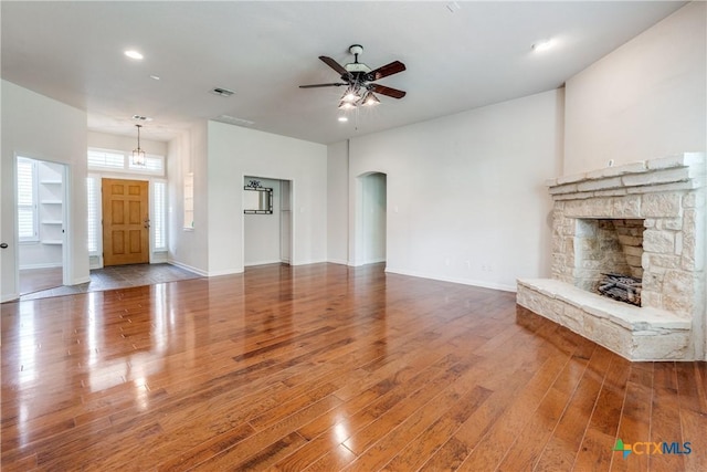 425 County Road 3830, San Antonio, TX 78253 - unfurnished living room with arched walkways, wood finished floors, a ceiling fan, a fireplace, and baseboards