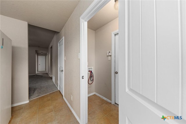 corridor with light tile patterned floors and a textured ceiling