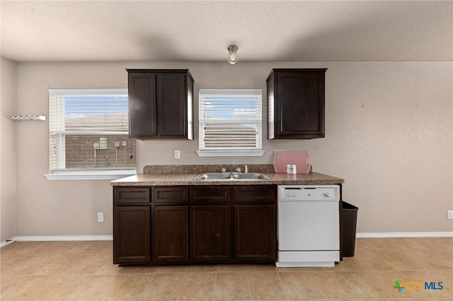 kitchen featuring dishwasher, sink, light tile patterned floors, and dark brown cabinetry