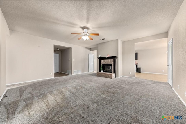 unfurnished living room featuring carpet floors, a textured ceiling, a fireplace, and ceiling fan