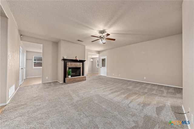 unfurnished living room with light carpet, a brick fireplace, a textured ceiling, and ceiling fan