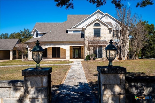 view of front facade featuring a shingled roof and a front lawn