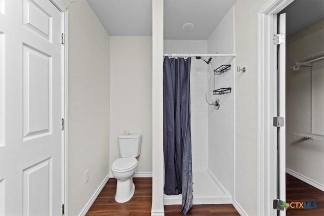 bathroom with a shower with curtain, hardwood / wood-style flooring, and toilet