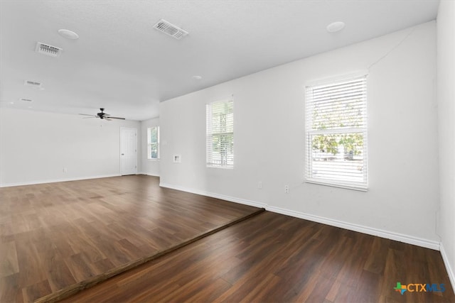 spare room with a wealth of natural light, ceiling fan, and dark hardwood / wood-style flooring