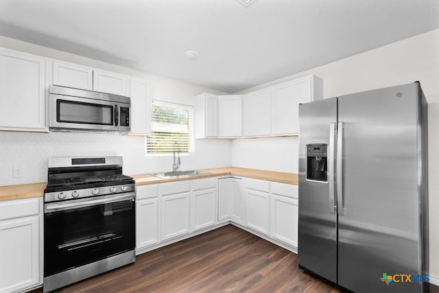 kitchen featuring wooden counters, dark hardwood / wood-style flooring, white cabinets, sink, and appliances with stainless steel finishes