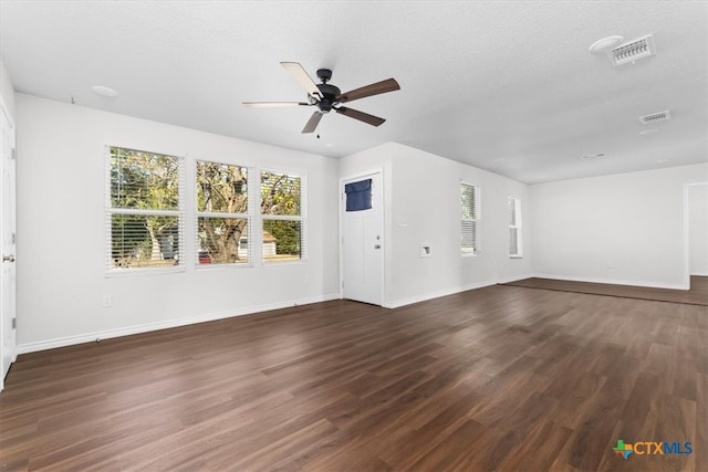 unfurnished living room with ceiling fan, dark hardwood / wood-style floors, and a textured ceiling