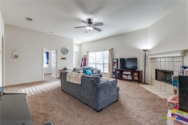 living room with light carpet, a tile fireplace, and ceiling fan