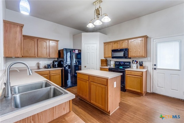 kitchen featuring sink, decorative light fixtures, light wood-type flooring, a kitchen island, and black appliances