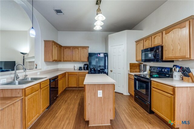 kitchen featuring sink, a center island, pendant lighting, light hardwood / wood-style floors, and black appliances