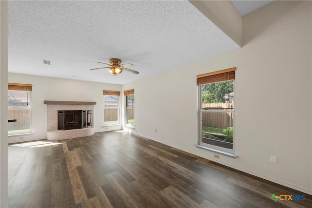 1007 Judy Ln, Copperas Cove, TX 76522 - unfurnished living room with wood finished floors, plenty of natural light, ceiling fan, a textured ceiling, and a brick fireplace