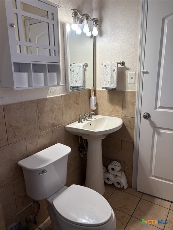 bathroom featuring tile patterned flooring, tile walls, and toilet