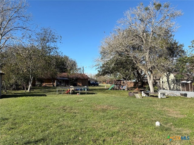 view of yard with a playground and a trampoline