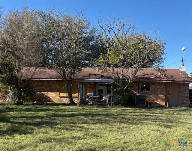 back of property featuring central AC unit and a lawn