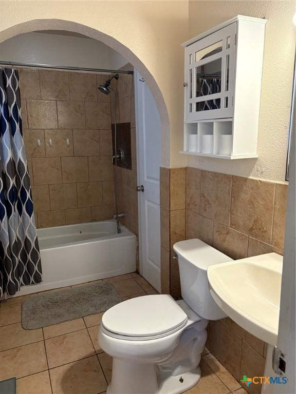 full bathroom featuring sink, tile walls, shower / bath combination with curtain, tile patterned floors, and toilet