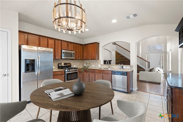 kitchen with light tile patterned flooring, pendant lighting, decorative backsplash, a notable chandelier, and stainless steel appliances