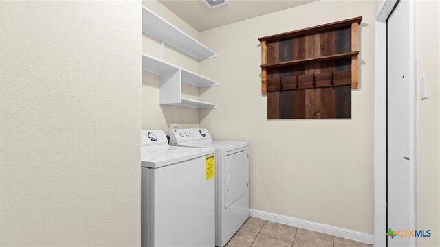 washroom featuring washing machine and clothes dryer and light tile patterned flooring