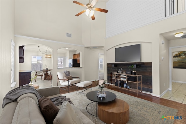 living room with a towering ceiling, ceiling fan, and light hardwood / wood-style flooring