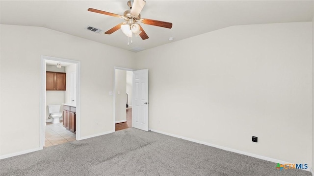 unfurnished bedroom featuring light carpet, ensuite bath, lofted ceiling, and ceiling fan