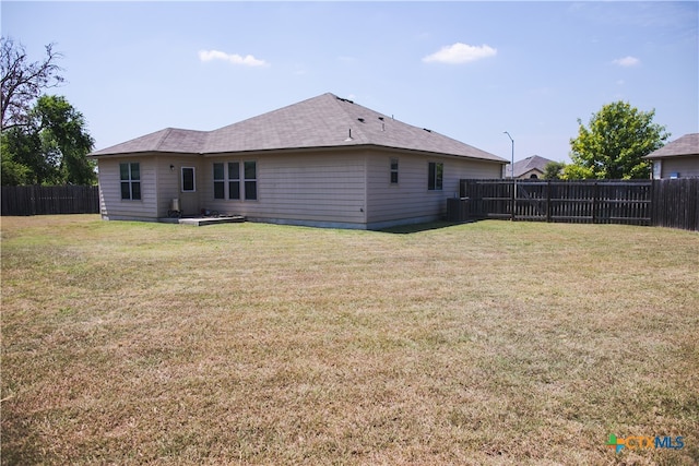 rear view of house featuring cooling unit and a lawn