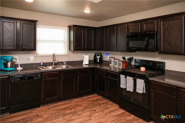 kitchen with dark brown cabinets, wood-type flooring, sink, and black appliances