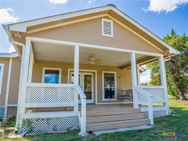 back of house featuring covered porch, ceiling fan, and a lawn