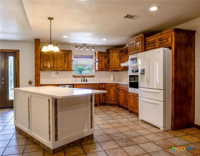 kitchen featuring hanging light fixtures, white appliances, a kitchen island, and tasteful backsplash