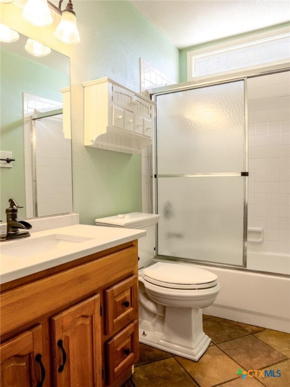 full bathroom featuring toilet, vanity, tile patterned flooring, and enclosed tub / shower combo