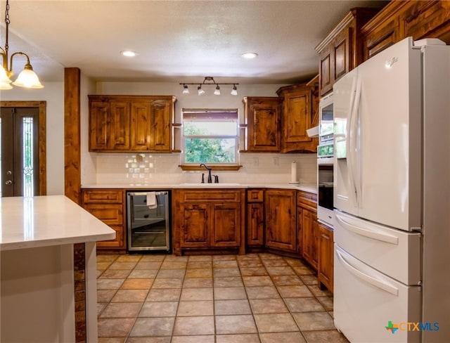 kitchen featuring wine cooler, decorative light fixtures, white fridge with ice dispenser, sink, and decorative backsplash