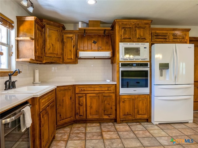 kitchen with backsplash, white appliances, and sink