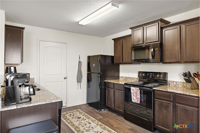 kitchen with dark wood-type flooring, dark brown cabinets, light stone countertops, a textured ceiling, and black appliances